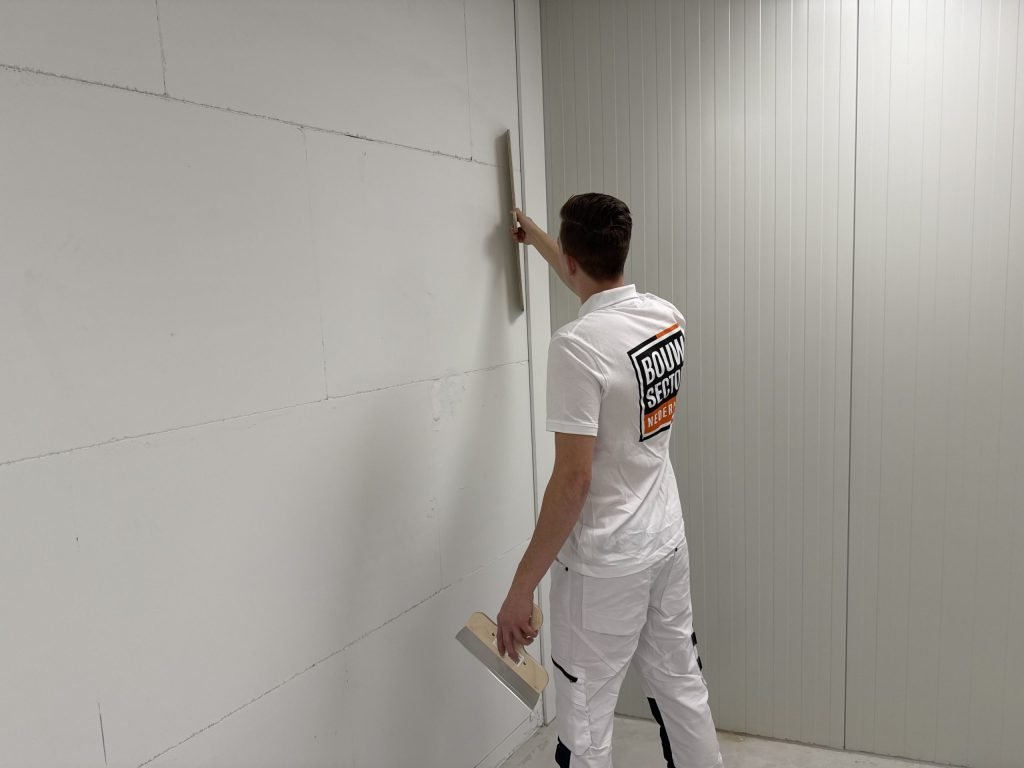 Vakman van Bouwsector Nederland controleert met een spaan een wand van gipsblokken